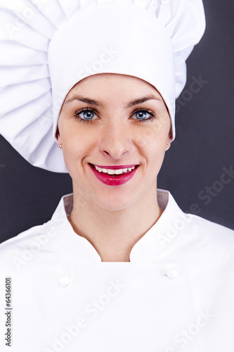Photo: Close-up woman cook look round or hear something, over dark wall Close-up woman cook look round or hear something, over dark wall