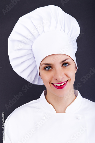 Photo: Close-up woman cook look round or hear something, over dark wall Close-up woman cook look round or hear something, over dark wall