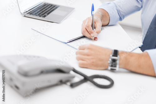 Photo: businessman writing in notebook businessman writing in notebook