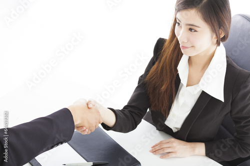 Photo: smiling business woman shaking hands with client in her office smiling business woman shaking hands with client in her office