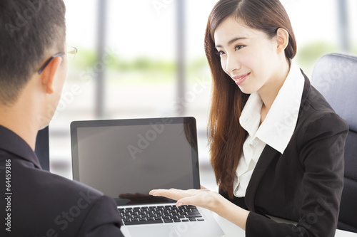 Photo: smiling Business woman showing at laptop and explaining a plan smiling Business woman showing at laptop and explaining a plan