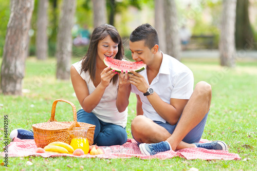 Photo: Portrait of a young couple eating watermelon at a picnic Portrait of a young couple eating watermelon at a picnic