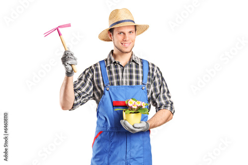 Photo: Male gardener holding flower plant and a mattock Male gardener holding flower plant and a mattock