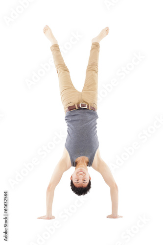 Photo: young man doing a handstand against on white background young man doing a handstand against on white background