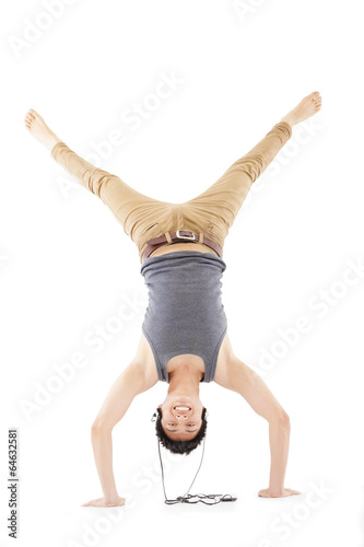 Photo: young man doing a handstand against and listening music young man doing a handstand against and listening music