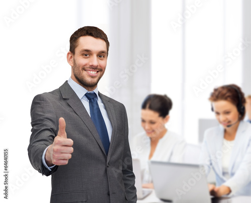 Photo: handsome buisnessman showing thumbs up in office handsome buisnessman showing thumbs up in office