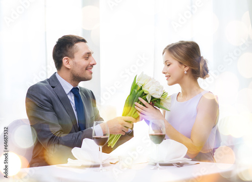 Photo: smiling man giving flower bouquet at restaurant smiling man giving flower bouquet at restaurant
