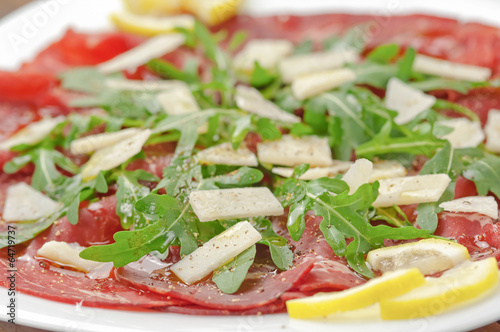 Photo: Closeup bresaola with arugula salad and olive oil Closeup bresaola with arugula salad and olive oil