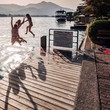 teenage girls jumping off a dock at lake teenage girls jumping off a dock at lake