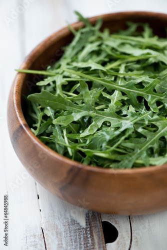 Photo: Fresh arugula in a wooden bowl, vertical shot Fresh arugula in a wooden bowl, vertical shot