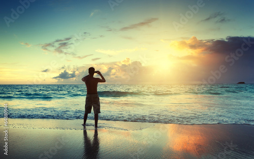 Photo: young man on the beach take photo on mobile phone young man on the beach take photo on mobile phone