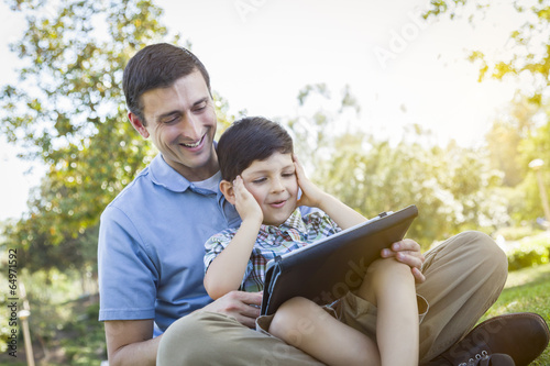 Photo: Handsome Mixed Race Father and Son Playing on Computer Tablet Handsome Mixed Race Father and Son Playing on Computer Tablet