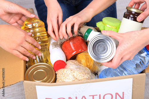 Photo: People makes foodstuffs out of donation box on grey background People makes foodstuffs out of donation box on grey background