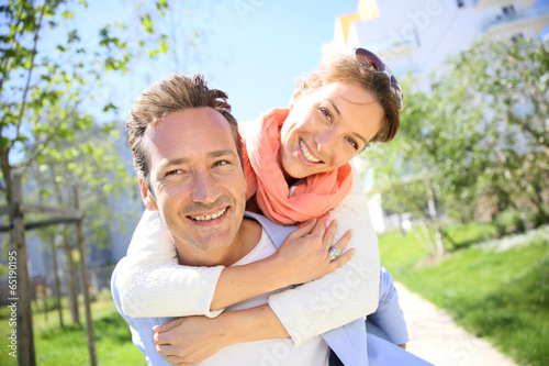 Photo: Man giving piggyback ride to woman in park Man giving piggyback ride to woman in park