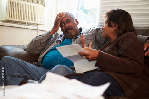 Photo: Worried Senior Couple Sitting On Sofa Looking At Bills Worried Senior Couple Sitting On Sofa Looking At Bills
