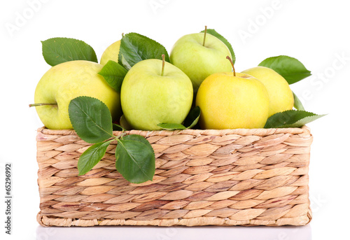 Fototapeta Ripe sweet apples with leaves in wicker crate, isolated on