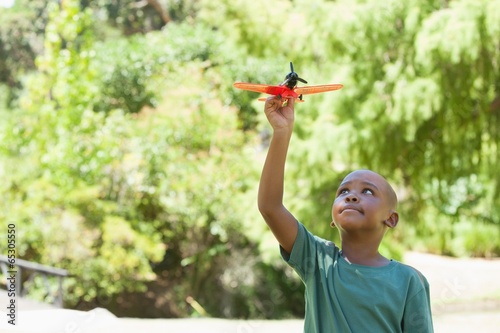 Photo: Happy little boy flying toy airplane Happy little boy flying toy airplane