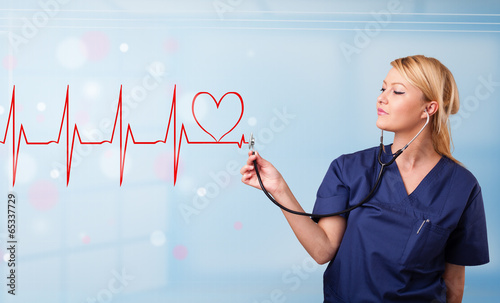 Photo: Young nurse listening to abstract pulse with red heart Young nurse listening to abstract pulse with red heart