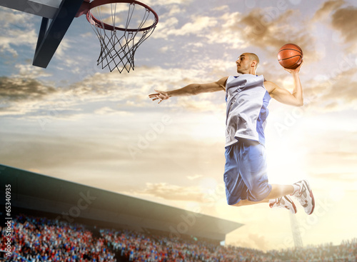Photo: Basketball player in action on background of sky and crowd Basketball player in action on background of sky and crowd