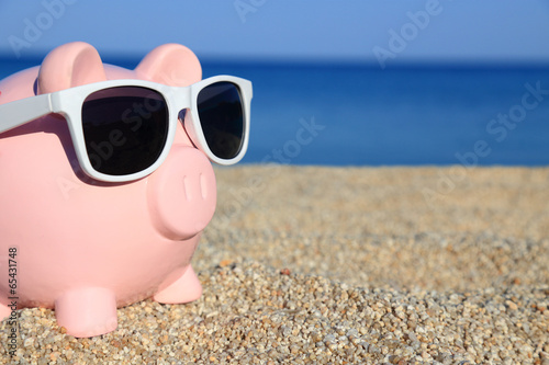 Photo: Summer piggy bank with sunglasses on the beach Summer piggy bank with sunglasses on the beach