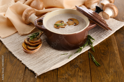 Photo: Mushroom soup in pot, on wooden background Mushroom soup in pot, on wooden background
