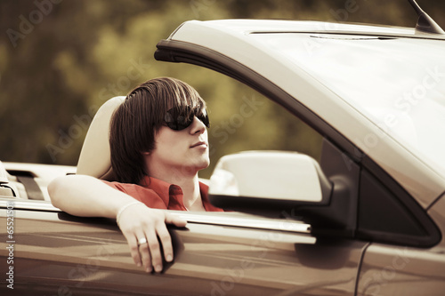 Photo: Young man driving a convertible car Young man driving a convertible car