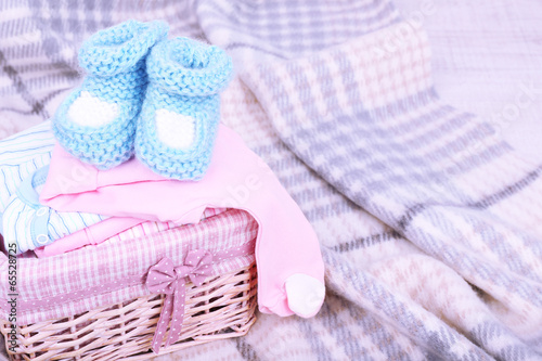 Photo: Baby clothes in basket on plaid in room Baby clothes in basket on plaid in room