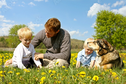 Photo: Father, Children, and Dog Relaxing in Flower Meadow Father, Children, and Dog Relaxing in Flower Meadow