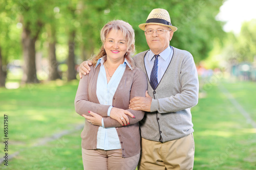 Photo: Mature couple posing in park on a beautiful sunny day Mature couple posing in park on a beautiful sunny day