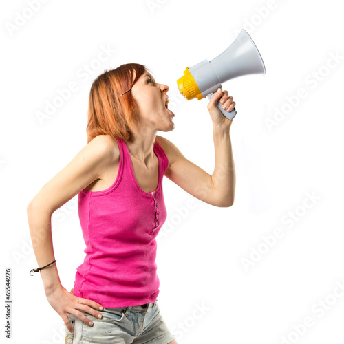 Photo: Redhead girl shouting with a megaphone over white background Redhead girl shouting with a megaphone over white background