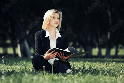 Photo: Young business woman with a folder in a city park Young business woman with a folder in a city park