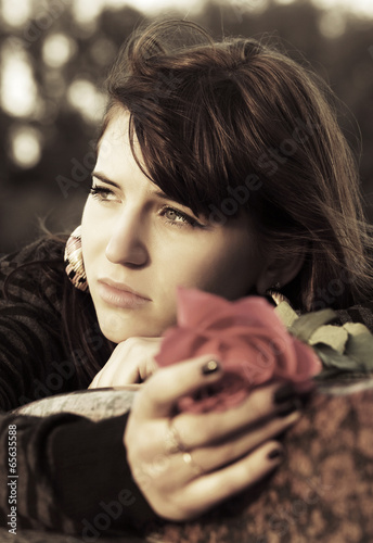 Photo: Sad young woman with a red rose Sad young woman with a red rose