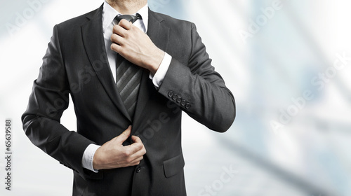 Photo: businessman corrects tie businessman corrects tie