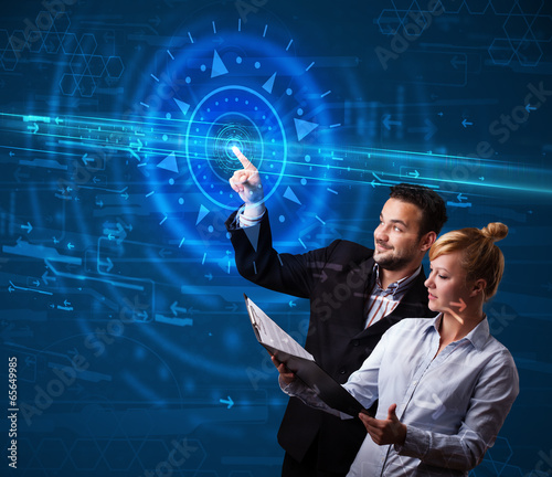 Photo: Young tech couple pressing high technology control panel screen Young tech couple pressing high technology control panel screen