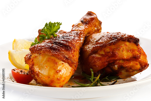 Photo: Grilled chicken legs and vegetables on white background Grilled chicken legs and vegetables on white background
