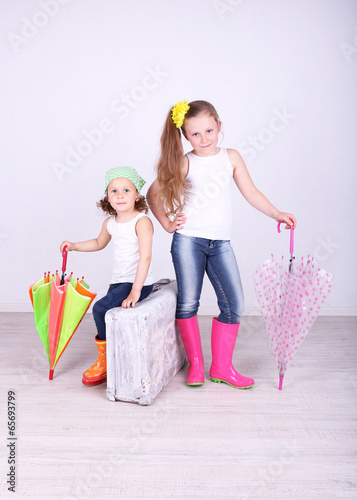 Photo: Beautiful small girls with suitcase on light background Beautiful small girls with suitcase on light background