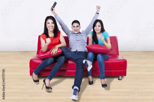 Photo: Happy young friends watching tv at home Happy young friends watching tv at home