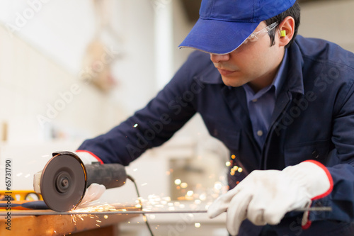 Photo: Worker using a grinder in a factory Worker using a grinder in a factory