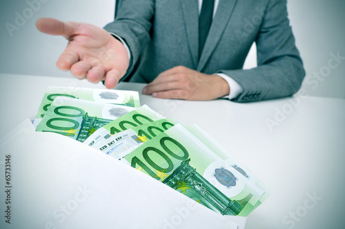 Photo: man taking an envelope full of euro bills man taking an envelope full of euro bills