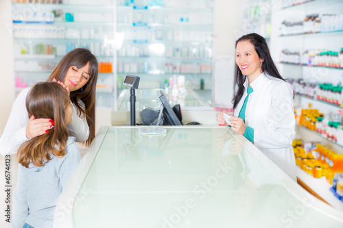 Photo: pharmacist giving vitamins to child girl in pharmacy drugstore pharmacist giving vitamins to child girl in pharmacy drugstore