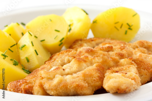 Photo: Golden fried schnitzel with boiled potatoes and chives. Golden fried schnitzel with boiled potatoes and chives.