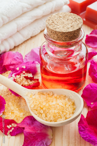 Photo: oil in glass bottle, sea salt, towel and rose petals oil in glass bottle, sea salt, towel and rose petals