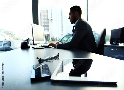Photo: Silhouette of businessman using laptop in office Silhouette of businessman using laptop in office