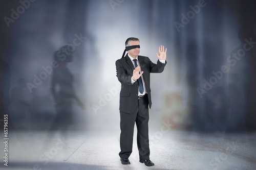 Photo: Composite image of mature businessman in a blindfold Composite image of mature businessman in a blindfold