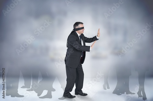 Photo: Composite image of mature businessman in a blindfold Composite image of mature businessman in a blindfold