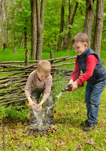 Photo: Two young boys extinguishing a small fire Two young boys extinguishing a small fire