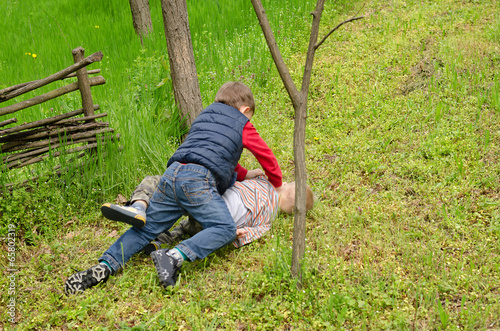 Photo: Two young boys fighting on the ground Two young boys fighting on the ground