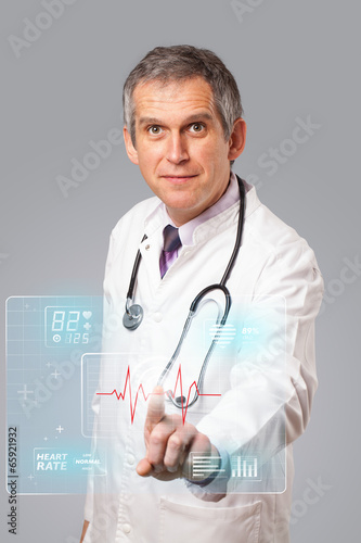 Photo: Middle aged doctor pressing modern medical type of button Middle aged doctor pressing modern medical type of button