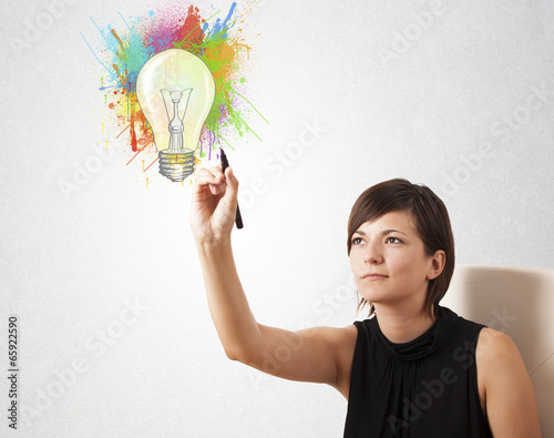 Photo: Young lady drawing a colorful light bulb with colorful splashes Young lady drawing a colorful light bulb with colorful splashes