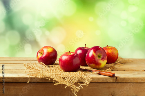 Photo: Apples on wooden table over autumn bokeh background Apples on wooden table over autumn bokeh background